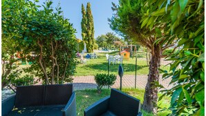 Ein Gartenbereich mit Korbmöbeln, einer kleinen Spielanlage und einem umzäunten Spielplatz.