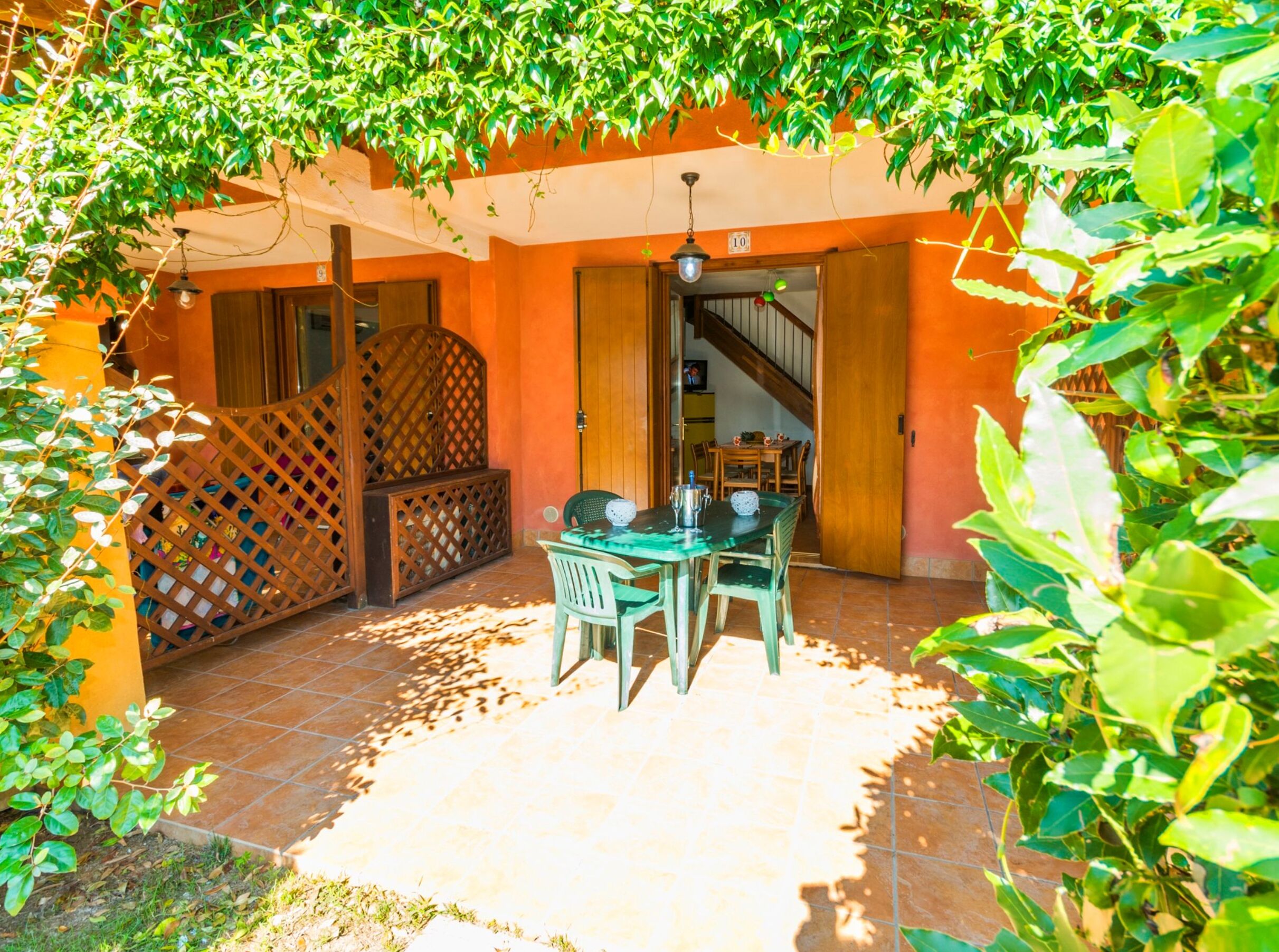 Un patio con una mesa y sillas de madera, rodeado de paredes anaranjadas y una valla de madera.