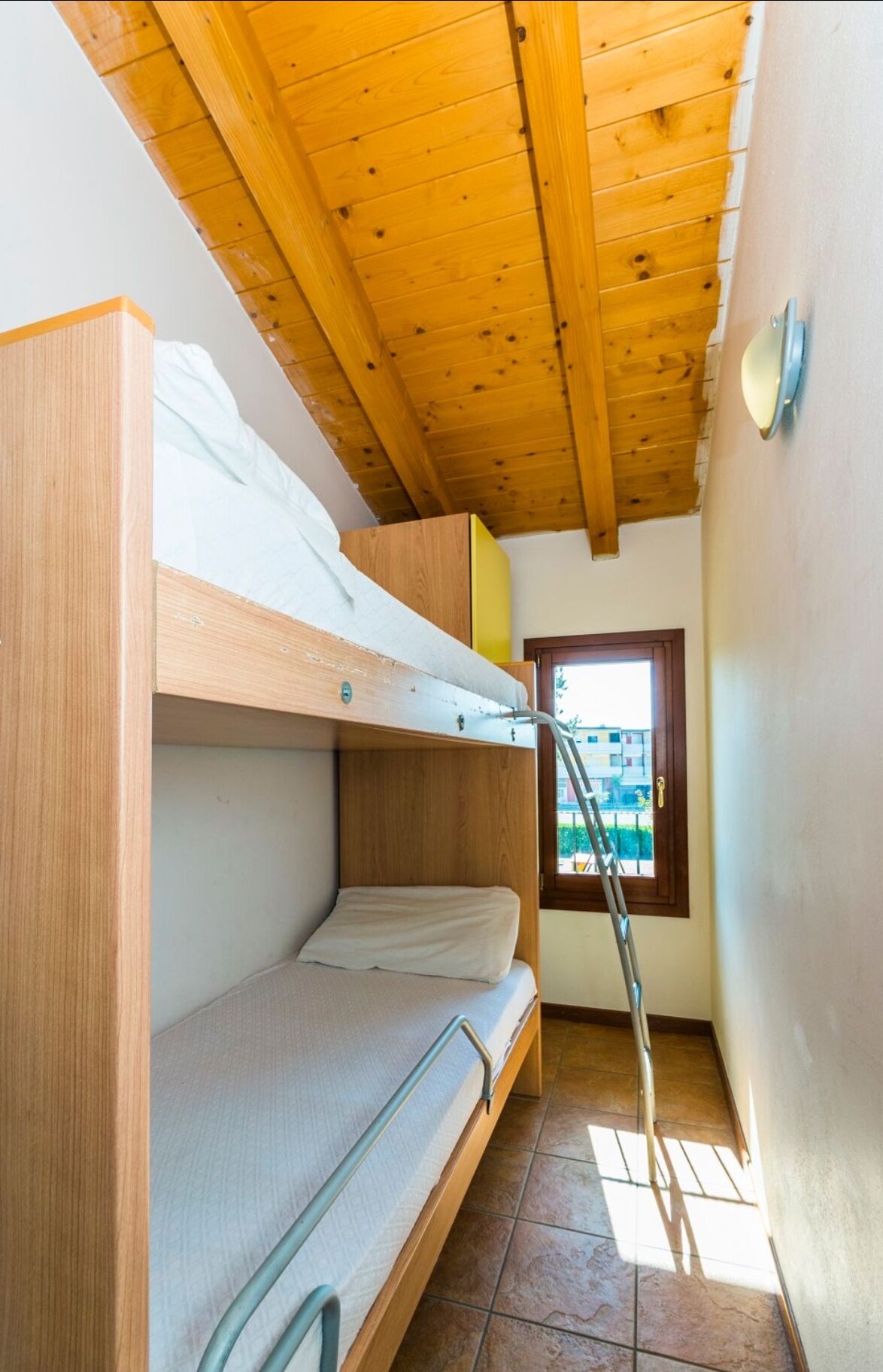 A compact room with bunk beds, a window with a view, and a ladder.
