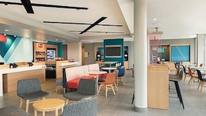 Un hall d’hôtel moderne avec un comptoir d’accueil, un espace salon et un écran de télévision.