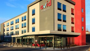 En modern hotellbyggnad med en tydlig skylt med texten ”avid”, många fönster och en ingång som är skyddad av ett tak.