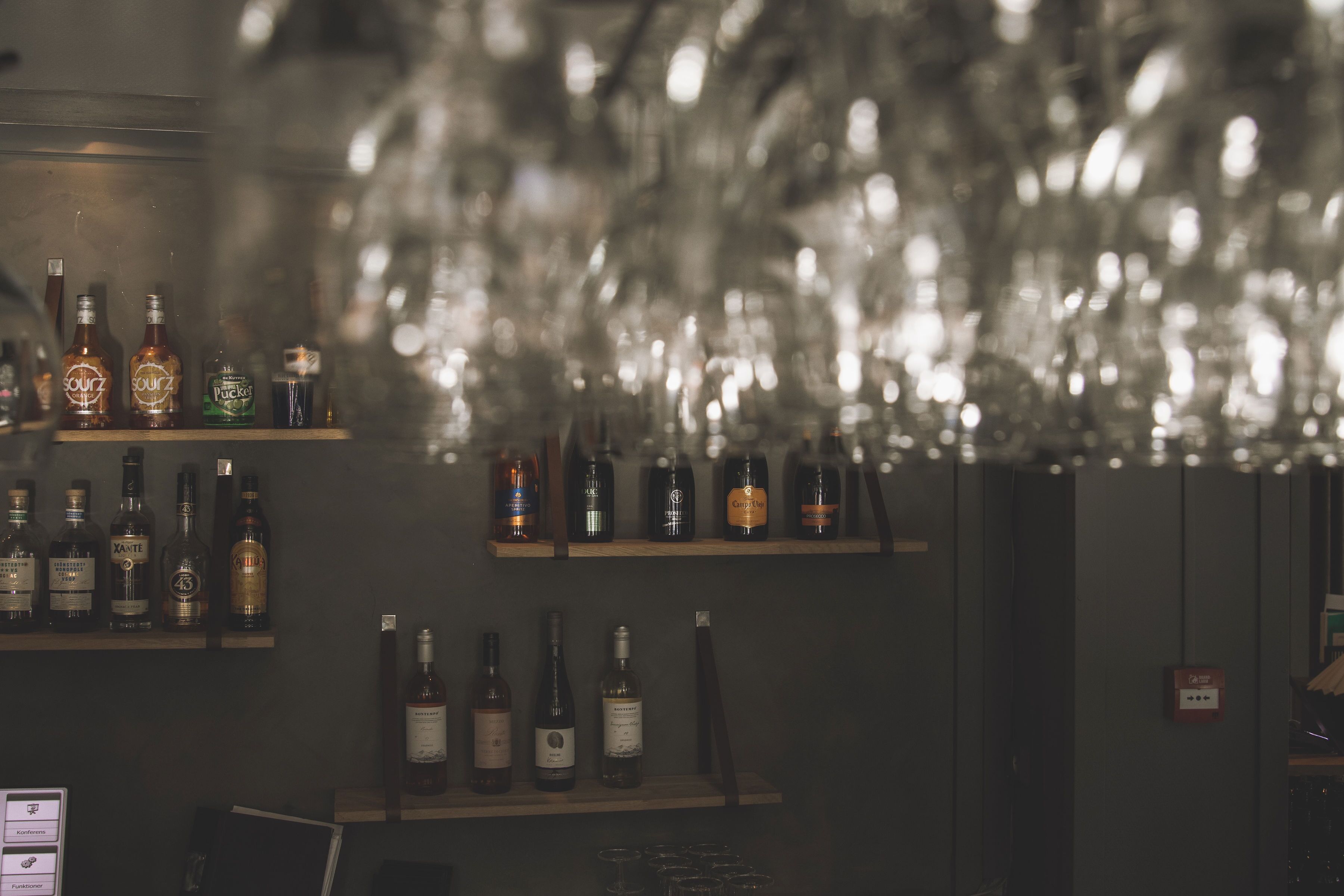 A bar area with shelves of various liquor bottles and glasses.