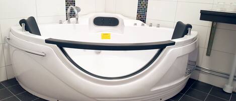 Una bañera blanca Whirlpool con un pasamanos de seguridad negro, un panel de control y una etiqueta de advertencia.