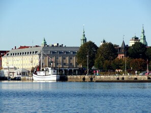 Vista al agua con un edificio histórico, un barco amarrado en el muelle y un cielo despejado.
