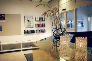 Un interior moderno con una vitrina de vidrio, una planta decorativa y obras de arte enmarcadas en la pared.