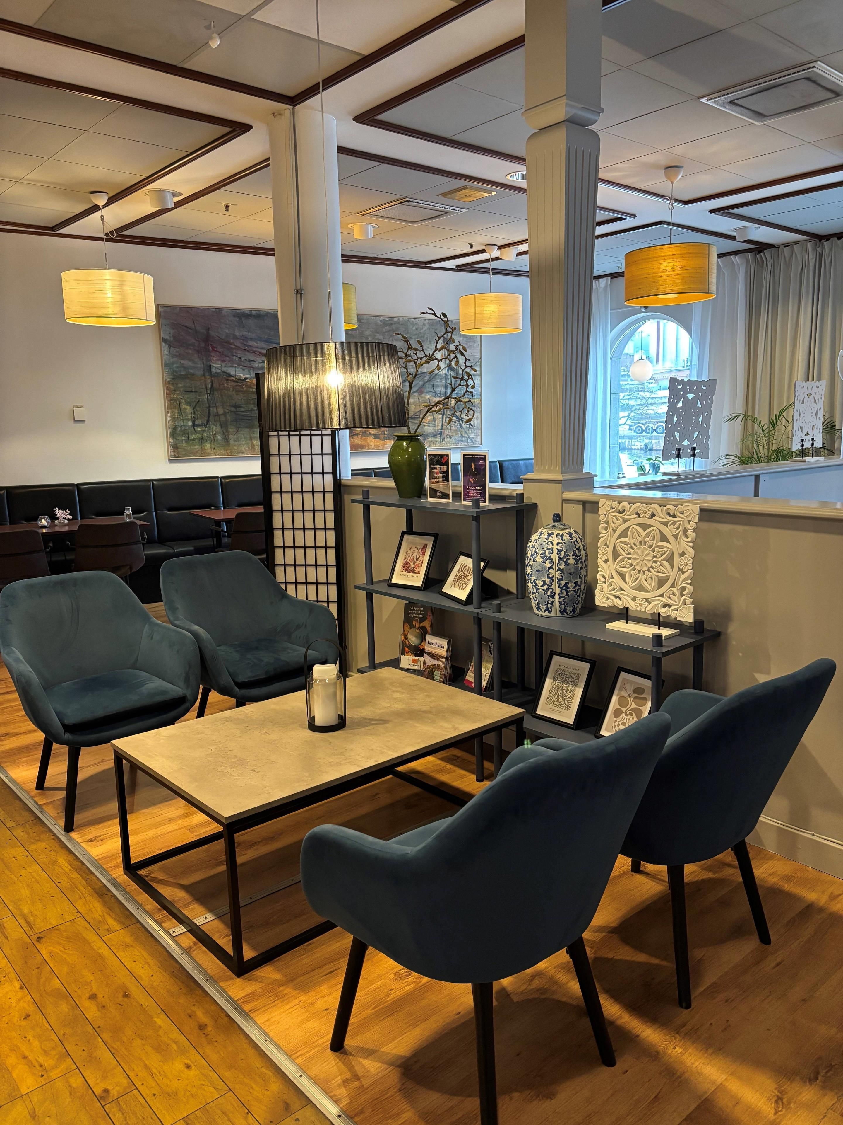 A modern lounge area with seating, a coffee table, decorative items, and a view through a window.