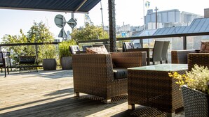 En træterrasse med fletningsmøbler og krukker med planter.