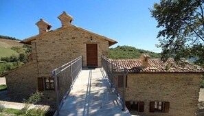 Traditional farmhouse with a sloped roof and wooden door, set amidst a rustic landscape.