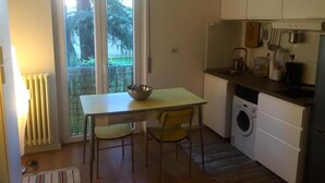 Una cocina funcional con una mesa y sillas, lavadora y vistas a través de una puerta corrediza de vidrio.
