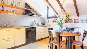 Una cocina moderna con armarios de madera, horno empotrado y comedor con mesa redonda y sillas.