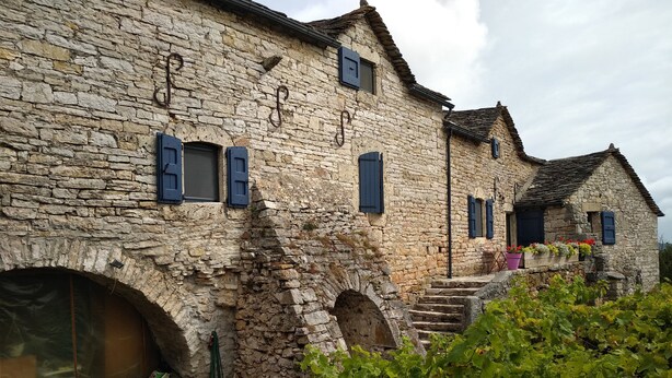 Ein Steinhaus mit Rundbogenfenstern und einer Treppe, die zu einer Veranda führt.