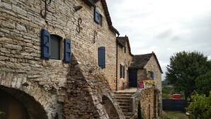 Ein Steinhaus mit rustikalem Äußeren, mit einer kleinen Veranda und Treppen, die zu einer Tür führen.