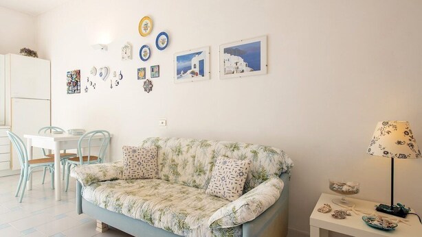 A living room with a sofa, a dining table with chairs, and wall art. - La Casa del Mare close to the beach (Nerano)