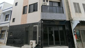 Un immeuble à plusieurs étages au design moderne, caractérisé par un mélange de façades en briques et en carreaux, de grandes fenêtres et une entrée imposante avec une porte en verre.