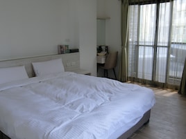 A hotel room with a large bed, a desk, and a chair.