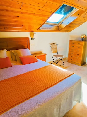 A bedroom with a bed, a nightstand, a chair, a dresser, and a skylight. - Duplex with 2 bedrooms (4 adults) (O Grove)