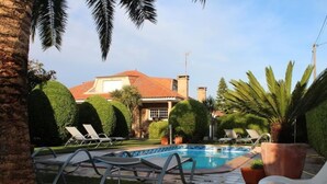 Un área de piscina con sillas de descanso y una casa al fondo.