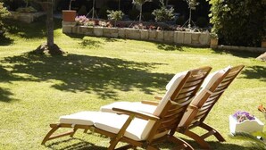 Dos sillones de madera con cojines sobre un césped cuidado.