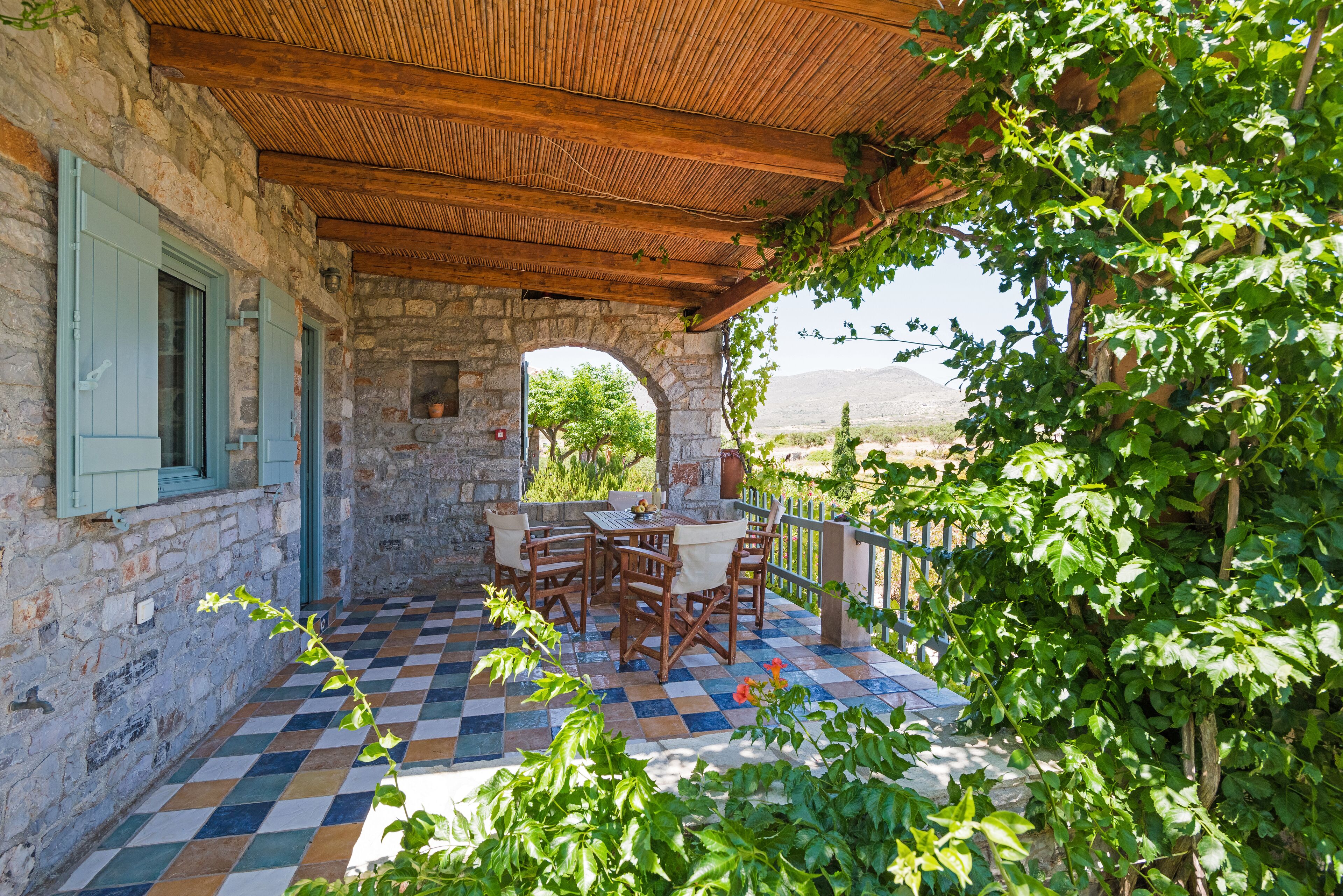 A stone building with a checkered floor, wooden furniture, and a view of the countryside.