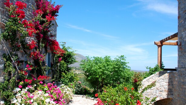 A stone building with a garden path leading to a wooden pergola. - Palaeopoli Villas (Kithira)
