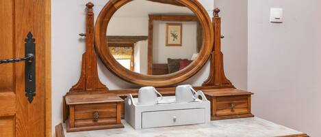 A wooden dresser with a marble top, a mirror, and a tray with cups.