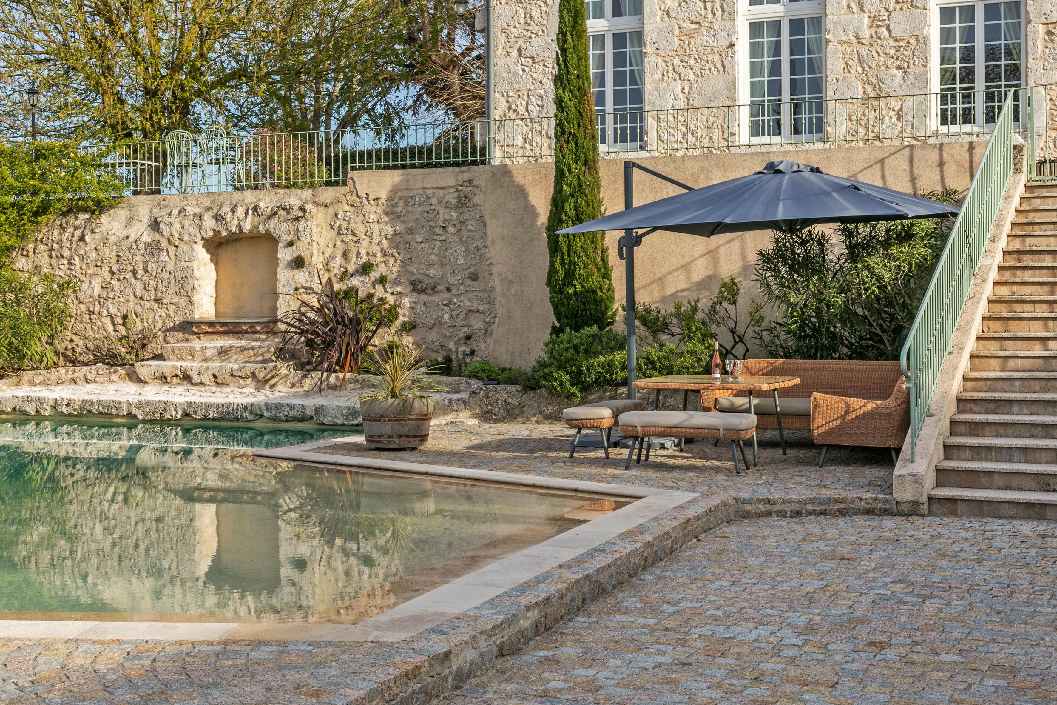 A stone building with a swimming pool, outdoor seating, and a staircase.