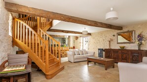 A spacious living room with a wooden staircase, a white sofa, a wooden coffee table, and a chessboard on a chair. - Domaine de Rambeau (Castelmoron-sur-Lot)