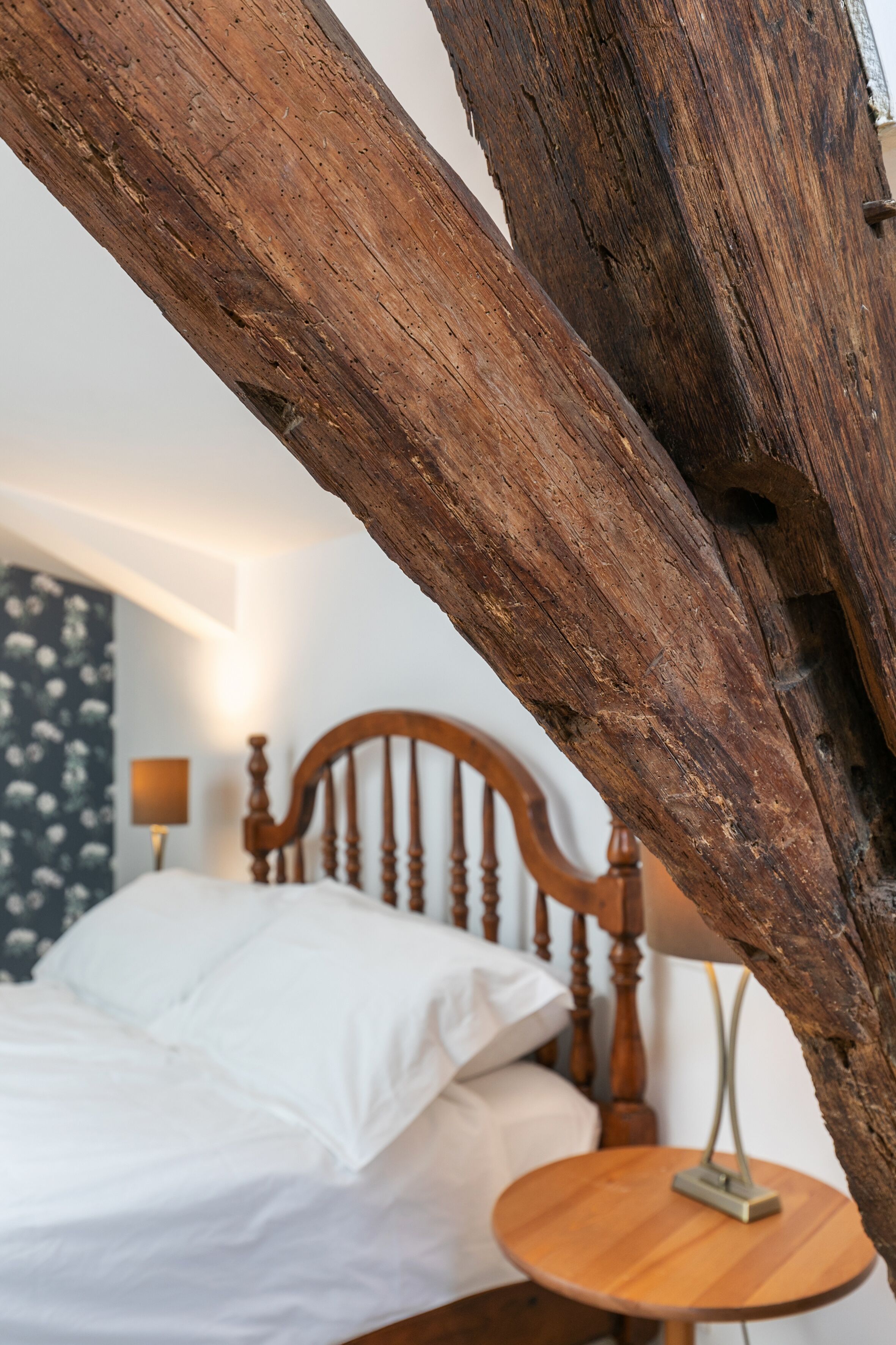 Ein Bett mit weißen Bettwäsche, einem Holzkopfteil und einem Nachttisch mit Lampe.