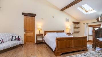 A bedroom with a wooden bed, a sofa, a skylight, and a wooden ceiling.