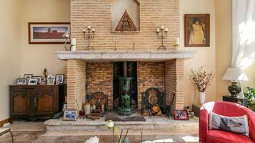 Uma sala de estar aconchegante com lareira de tijolos, móveis de madeira e diversos objetos decorativos.
