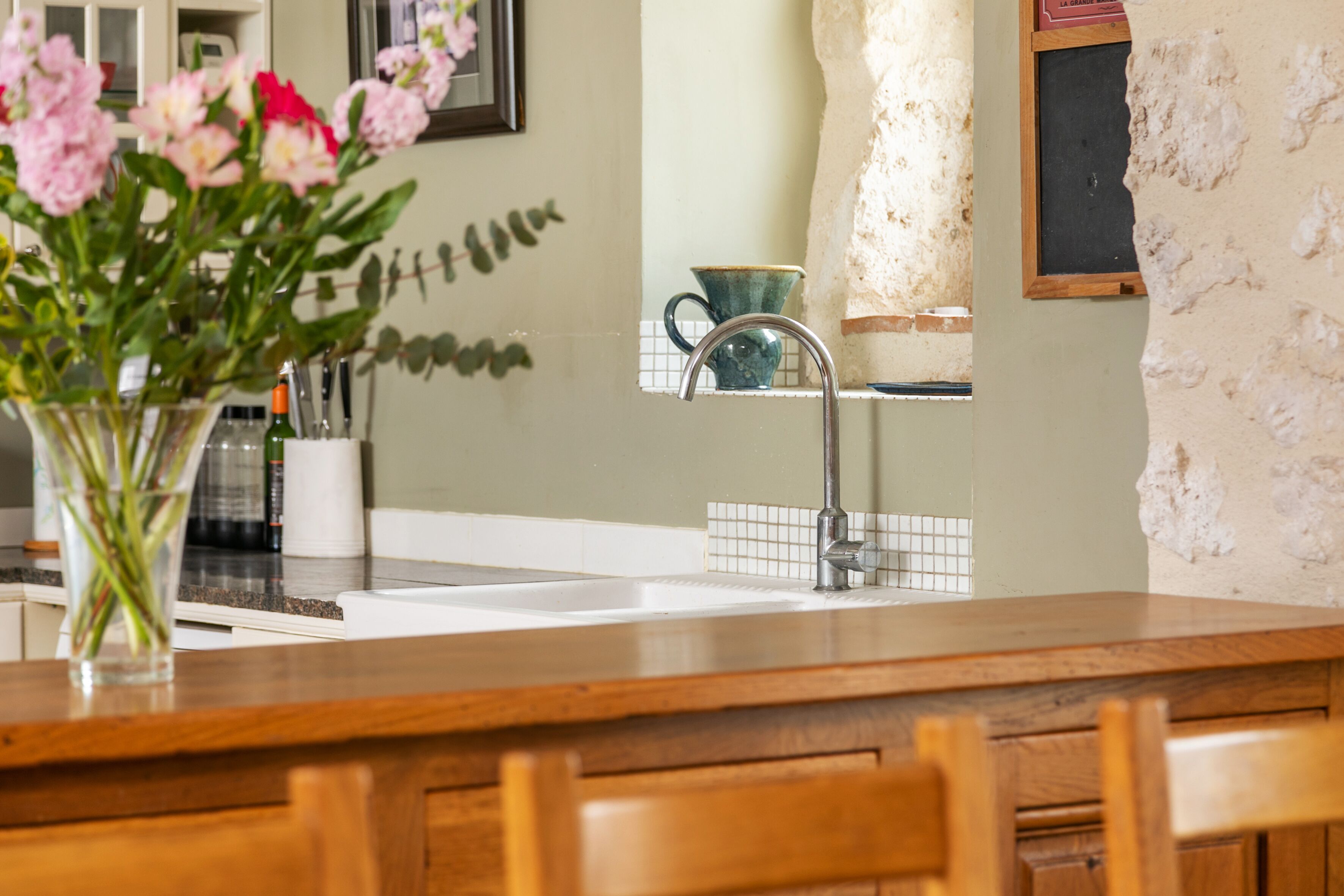 Una cocina con encimera de madera, un fregadero y un jarrón de flores.