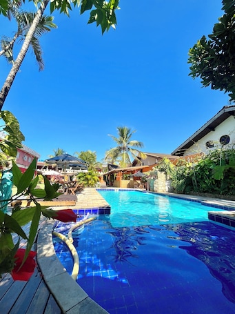 Una piscina al aire libre, sombrillas, sillones reclinables de piscina