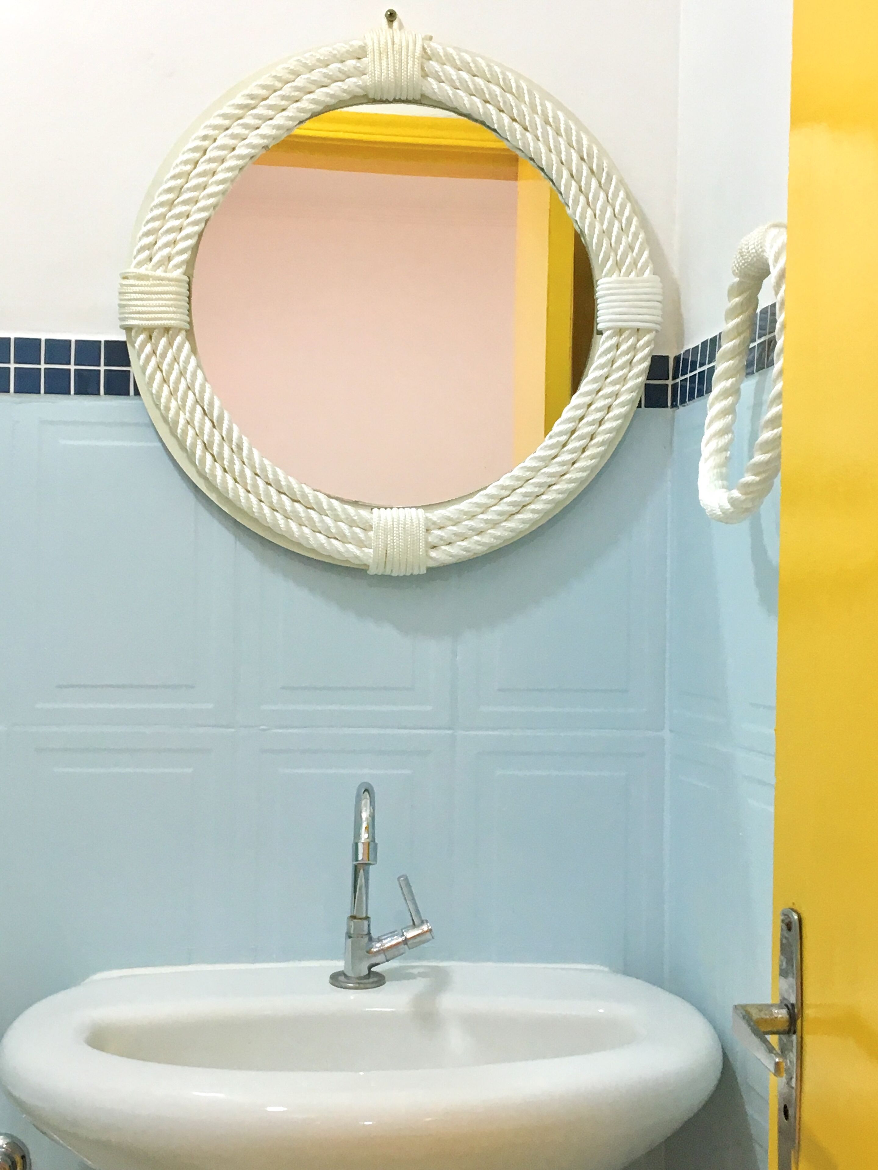 Un baño con un espejo redondo, un lavamanos y una puerta.