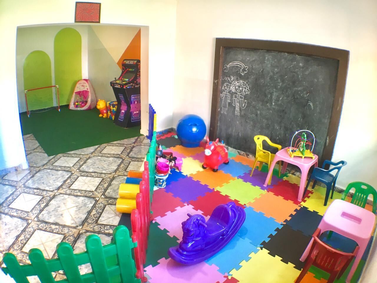 A playroom with colorful foam mats, toys, and a chalkboard.
