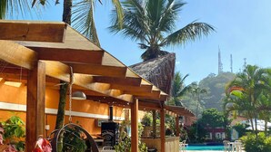 A resort with a pool, outdoor seating, and palm trees. - Pousada Dolce Vita (Itanhaém)