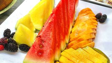 A buffet with various food items including sliced watermelon, mango, pineapple, and blackberries.