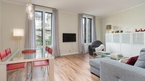 Una sala moderna con comedor, ventanas amplias, un televisor de pantalla plana y un sofá.