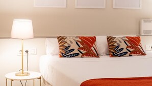 Habitación de hotel con cama, lámpara de noche y tres cuadros en la pared.