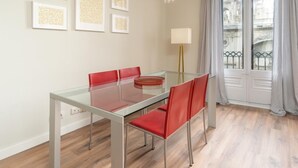Un comedor con una mesa de vidrio y sillas rojas, una lámpara y obras de arte enmarcadas en la pared.
