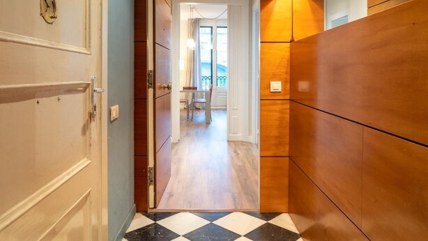 Un pasillo con suelo de cuadros, paredes de madera y una puerta con picaporte de latón.
