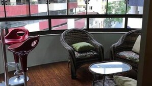 A room with wicker furniture, a small round table, and a red bar stool. - Apto Perfeito Quadra Mar (Balneário Camboriú)
