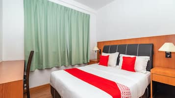 A hotel room with a bed, two bedside tables, a chair, a desk, and a window with curtains.