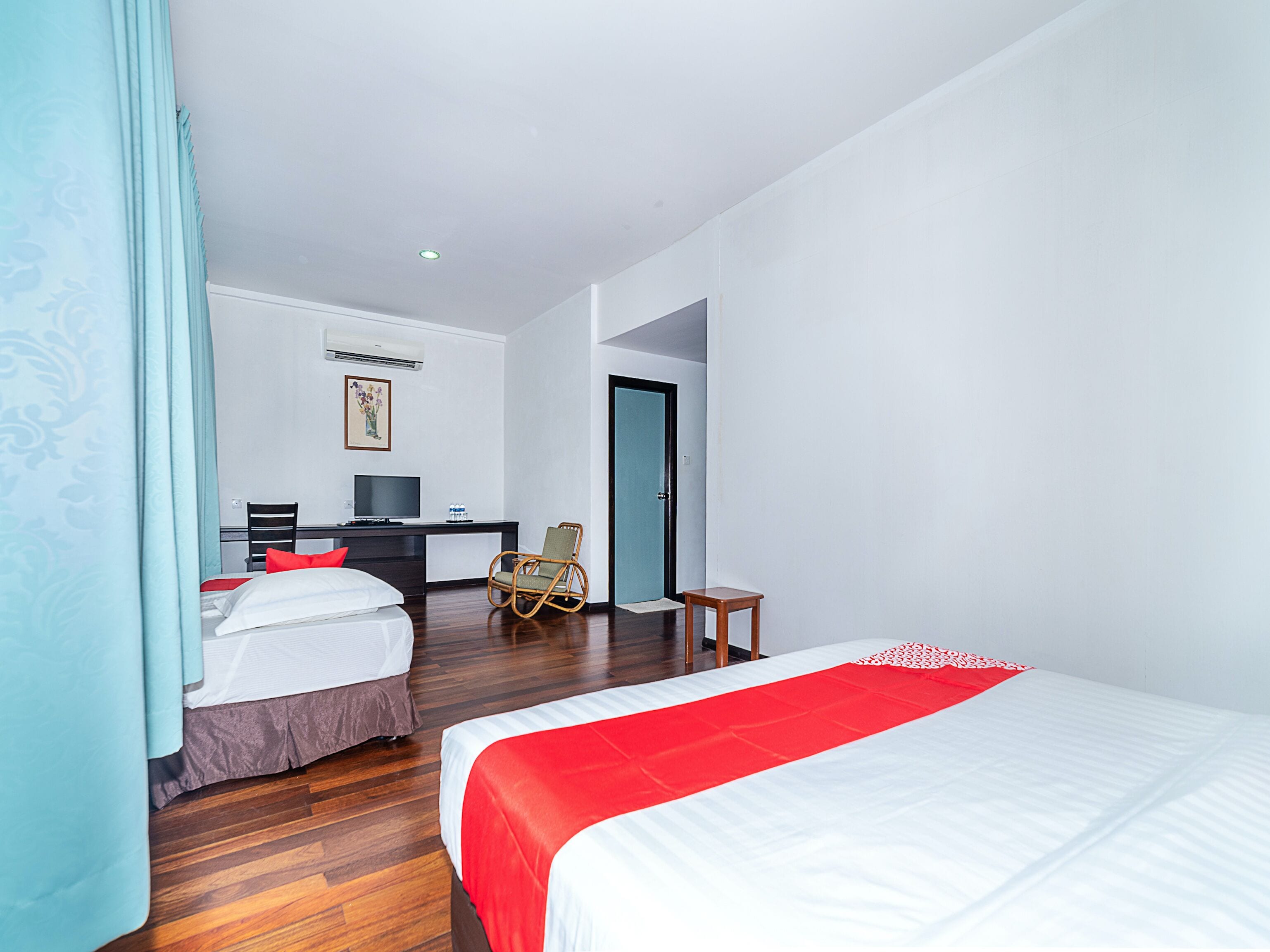 Une chambre d’hôtel avec deux lits, un bureau avec un ordinateur, une chaise et une porte.