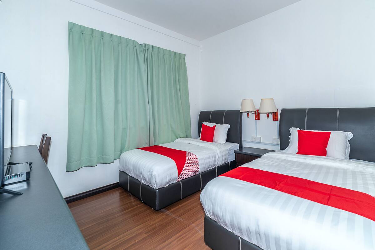 Una habitación de hotel con dos camas, un escritorio y una cortina verde.