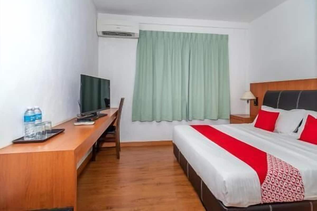 Una habitación de hotel con cama, escritorio con computadora, televisor y ventana con cortinas.