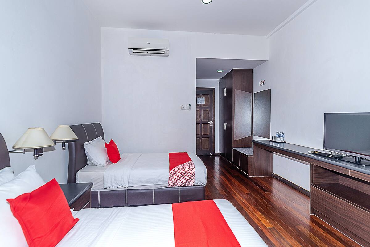 Una habitación de hotel moderna con cama, lámparas de noche, escritorio con televisor de pantalla plana y armario.