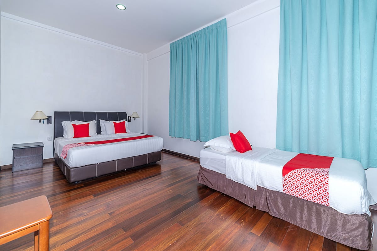 Habitación de hotel con dos camas, suelo de madera y cortinas color turquesa.