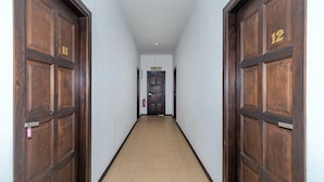 Un pasillo con puertas de madera, un extintor y un letrero que indica la dirección hacia la cocina.