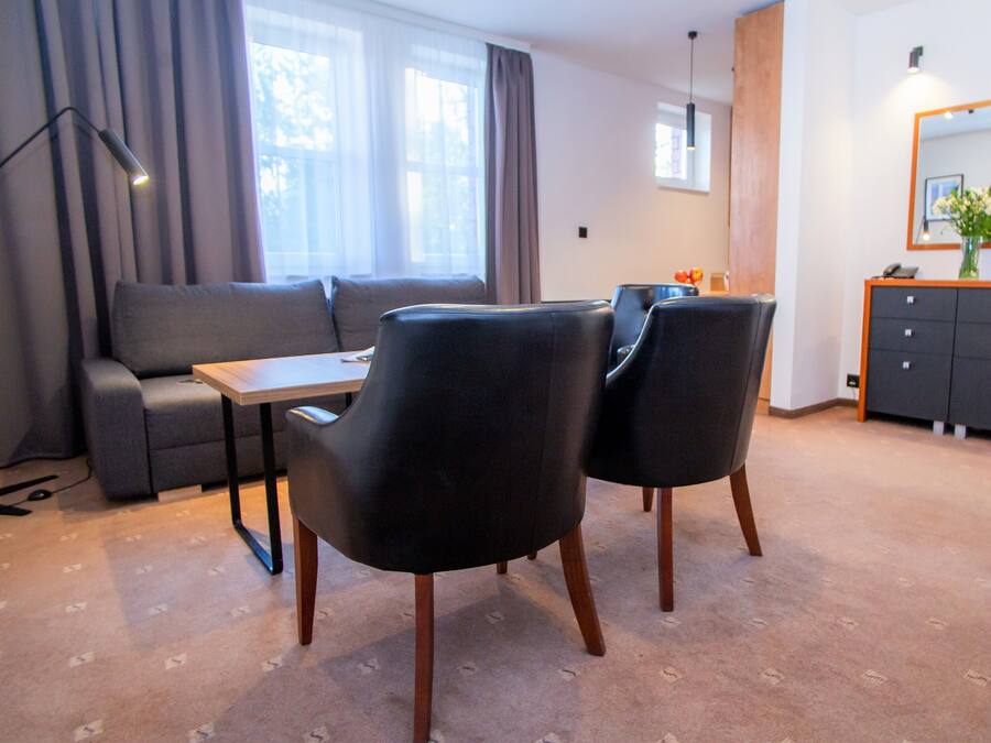 A modern living room with a sofa, two armchairs, a small table, and a cabinet.