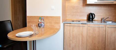 A compact kitchen with a microwave, sink, and a small dining area with a table set for two.